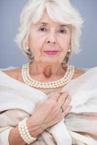 Elegant, senior woman with pearl necklace and bracelet, wearing white shawl