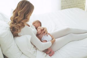 Smiling happy beautiful mother breastfeeding her baby infant