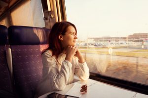 Young woman traveling looking out the window while sitting in the train.